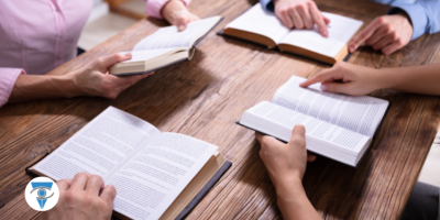 Un grupo de personas alrededor de una mesa, sostienen sus libros.