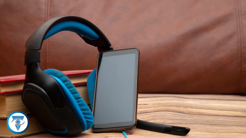 Un par de auriculares y un teléfono celular apoyados sobre varios libros.